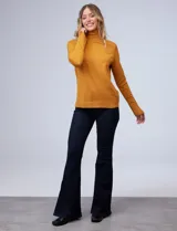 Polera de punto fino marca Nienty, color blanco, con cuello alto volcado y mangas largas con detalle de tajo en los puños.