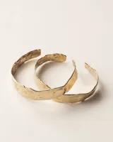 Pulsera tipo esclava abierta, con acabado rústico y textura irregular, en tono plateado. Se vende por unidad.