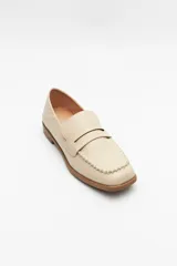 Mocasines color beige de símil cuero, con punta cuadrada, detalle de bordado a tono en la capellada y taco de 2,5cm.