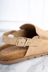 Zueco color beige de gamuza, con plantilla de corcho, detalle de costuras en la parte delantera y tira trasera ajustable con hebilla.