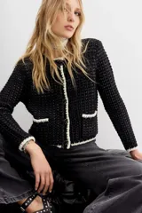 Cardigan negro con textura y detalles en blanco.