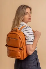 Mochila color marrón de símil cuero con un compartimento principal amplio, bolsillo al frente con cierre, correas ajustables y asa.