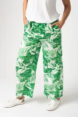 Pantalón palazo verde con estampado de hojas de palmera blancas, cintura elastizada con lazo y corte amplio.