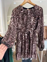 Vestido corto con estampado animal print, de mangas largas traslúcidas y falda con volados.