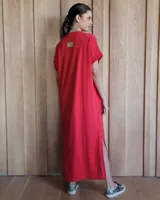 Vestido largo color crudo con cuello redondo y mangas cortas con ribete negro. Tiene corte recto y aberturas laterales en el ruedo.