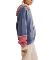 Hoodie oversized color azul desgastado con capucha y bolsillo canguro. Presenta un cuello y puños de tejido de punto con patrón a rombos en rojo y blanco, y cordones gruesos de color crema.