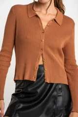 Cardigan negro de tejido de punto acanalado, con cuello polo, corte al cuerpo y cierre frontal con botones.