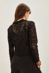 Saco corto de encaje negro con solapas de satén y un botón frontal.