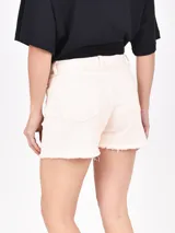 Short de jean color crudo, tiro alto, con bolsillos delanteros y traseros, y ruedo desflecado.