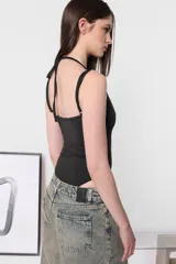 Body blanco de microfibra al cuerpo con tiras finas superpuestas en escote y espalda. Broches snap en entrepierna y elástico interno en contorno de tiro.