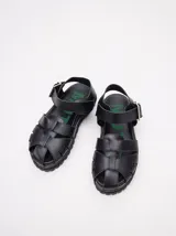 Sandalias romanas color verde oliva, con tiras entrecruzadas y hebilla lateral. Suela de goma negra con plataforma de 3cm. Fabricadas en cuero vacuno.