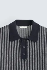 Polo de hombre de corte relajado, tejido de punto de algodón a rayas verticales en tonos gris y negro. Tiene cuello solapa, cierre frontal con botones y mangas cortas.