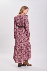 Vestido largo de corte holgado con estampado floral en tonos rosa y marrón. Tiene escote en V, mangas largas abullonadas y cinturón marrón de cuero sintético.