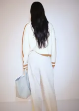 Sweater de punto grueso color crema con cuello alto con cierre de cremallera y detalle de rayas marrones en contraste en mangas y ruedo.