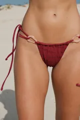 Bombacha de bikini colaless negra, con argollas decorativas de resina color hueso en los laterales.