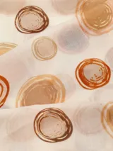 Pañuelo rectangular de tela fina color crema con estampado de círculos concéntricos en tonos marrones.
