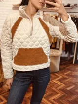 Sweater blanco con diseño acolchado, cierre parcial con cremallera, detalles en cuero color marrón y bolsillo tipo parche en el frente.