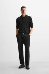 Pantalón negro de corte recto con cintura elástica ajustable con cordón, bolsillos laterales y traseros.