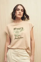 Remera color beige claro de manga corta con estampado floral y tipográfico en verde.