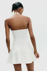 Vestido corto blanco de tejido de punto elástico, con cuello halter, escote corazón y cierre con botones en el cuello.