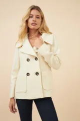 Chaquetón color crema con doble solapa, abrochadura doble, bolsillos delanteros y forro al tono.