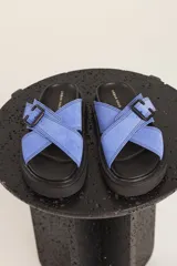 Sandalias planas color beige con tiras cruzadas y hebilla decorativa.