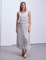 Vestido largo sin mangas, con estampado a rayas verticales en tonos beige, marrón y blanco. Tiene escote redondo y corte a la cintura con punto smock.