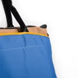 Cartera de nylon azul combinada con diseño elegante, cuenta con asas y cierre superior.