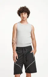 Bermuda negra de textil liviano con calce oversize, elástico y cordón de ajuste en la cintura. Presenta recortes con ribetes reflectantes grises en los bolsillos delanteros y ribetes blancos en el ruedo. Posee bolsillos traseros.