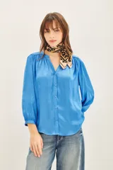 Camisa blanca de poliéster con cuello mao y mangas largas con frunces en hombros, mangas y espalda.