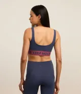 Top deportivo negro de microfibra con breteles anchos, copas desmontables, recorte cut-out en el busto y banda elástica con estampado de letras "Keep Moving".