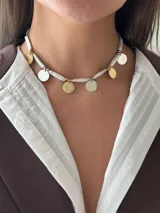 Collar corto con perlas de río naturales, cuentas metálicas de acero quirúrgico, medallitas bañadas en plata y oro y mostacillas. Se cierra con cadena de acero quirúrgico y ganchito para regular el largo.
