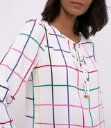 Blusa de crepe blanca con estampado a cuadrillé en tonos azul, rojo, verde y negro. Tiene mangas largas con puños elásticos y ajuste con lazos en el escote.