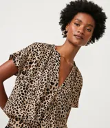Blusa de crepé color beige con estampado de leopardo, escote en V, manga corta y bajo elástico.