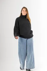 Sweater negro tejido en punto arroz, con cuello alto, mangas largas y silueta holgada.
