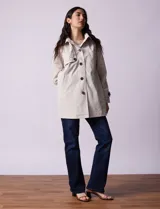 Gabardina impermeable color beige, marca Weatherproof, con abertura central con botones, bolsillos delanteros y capucha desmontable.