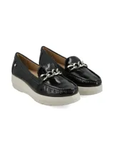 Mocasín de cuero charol negro con plataforma blanca y detalle de hebilla metálica plateada en el empeine.