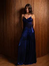 Vestido largo metalizado color negro, con tirantes finos, escote en V, falda plisada y espalda abierta con nudo.