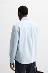 Camisa azul marino de algodón con textura jacquard, corte relaxed fit, cuello solapa, manga larga con puños abotonados y cierre frontal con botones.
