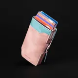 Billetera doble de cuero marrón con detalles en rosa. Cuenta con doble caja de aluminio con sistema de deslizamiento para tarjetas, clip para billetes y espacio adicional para documentos.