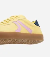 Championes color amarillo con detalles laterales en lila y talón en azul marino.