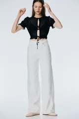 Top corto de punto calado negro con escote redondo, frente abierto con lazos y mangas cortas abullonadas con volados.