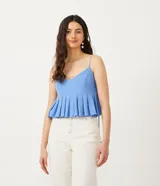 Blusa cropped celeste de lino, con escote en V, tirantes finos ajustables con nudos, elástico en la espalda y detalle de pliegues en el ruedo.