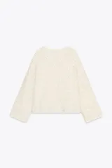 Chaqueta color crema de tejido de punto con lentejuelas, cuello barco, manga larga y cierre frontal con botones.