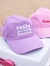 Gorro de visera color lila, estilo dad hat, de lona lavada con bordado frontal en blanco que dice "RUSTY AUSTRALIA MERMAID BEACH".