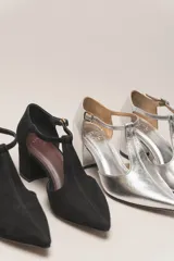 Zapato de vestir negro de cuero, con punta fina, tira en forma de T y hebilla lateral.