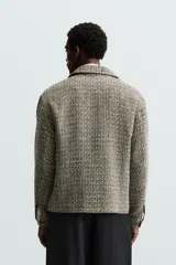 Sobrecamisa de hombre regular fit confeccionada en tejido con estructura irregular en tonos beige, marrón y negro. Tiene cuello solapa, manga larga con puños abotonados, bolsillos laterales y cierre frontal con cremallera.