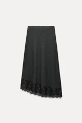 Falda midi gris oscuro de tejido de punto, con cintura elástica y bajo asimétrico con detalle de encaje negro.