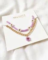 Set de joyería de collar y pulsera con cuentas en tonos lilas y flores blancas.