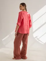 Camisa color coral de lino, corte holgado, escote redondo y mangas 3/4 ajustables con botón.